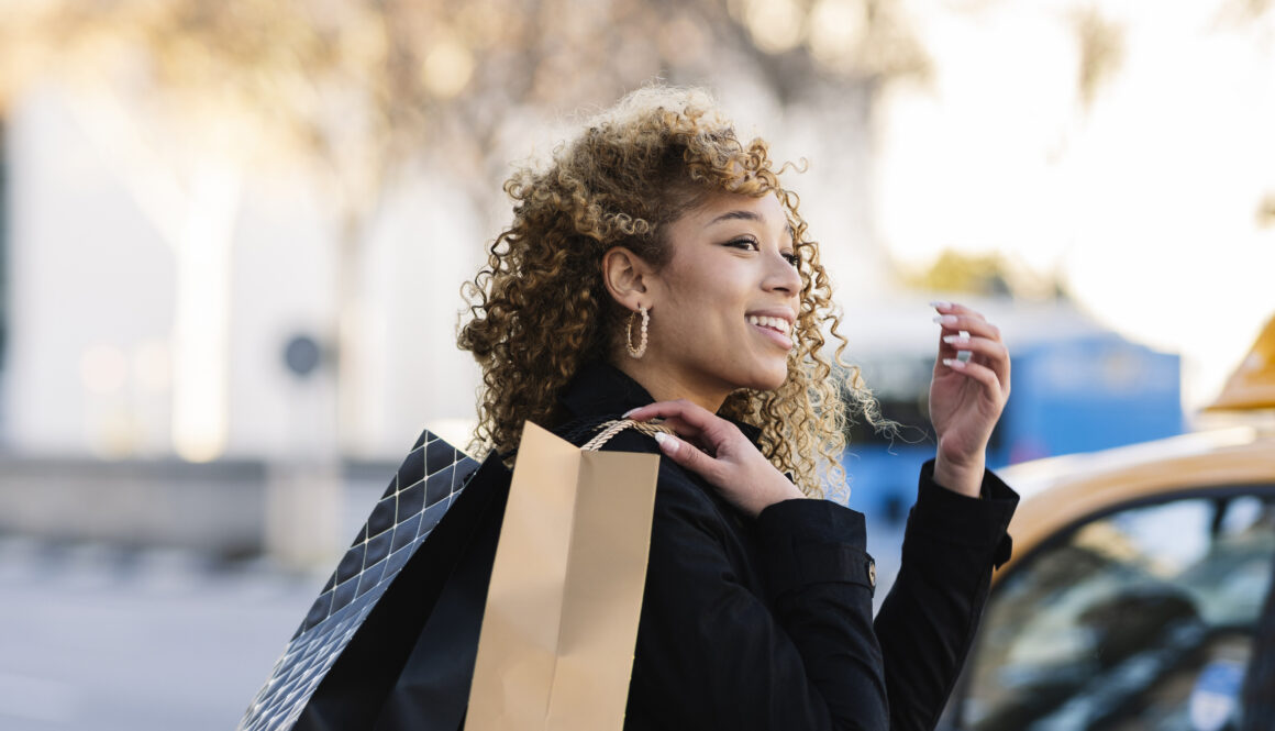 Pretty Hispanic woman with curly hair walking with shopping bags through the city,